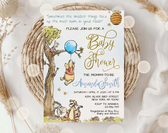 May include: A rectangular baby shower invitation card featuring Winnie the Pooh characters, a blue balloon, and a beehive. Text includes: Sometimes the smallest things take up the most room in your heart, Baby Shower, Amanda Smith, April 17, 2025, 5 PM, 4254 Silver Bird Street, New York, NY 90040, RSVP 123-456-789, Registered at Buy Buy Baby and Amazon.