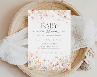 Op de afbeelding: Een rechthoekige uitnodigingskaart voor een babyshower met aquarelillustraties van wilde bloemen in roze, blauwe en gele tinten, met de tekst BABY in bloom en de evenementgegevens voor Monica Williams.