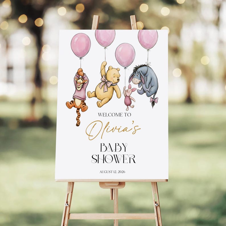 Pu&ograve; includere: Un cartello bianco per baby shower su un cavalletto presenta illustrazioni dei personaggi di Winnie the Pooh che tengono palloncini rosa. Il cartello recita "Benvenuti al Baby Shower di Olivia" con la data del 12 agosto 2026.