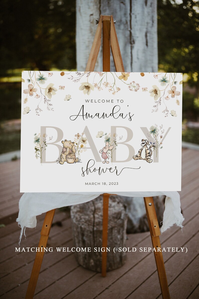 Pode incluir: Um cartaz de boas-vindas ao ch&aacute; de beb&ecirc; de Amanda com os personagens Winnie the Pooh e Piglet. O cartaz &eacute; branco com um design floral e o texto "Bem-vindo ao ch&aacute; de beb&ecirc; de Amanda" em fonte de caligrafia preta. A data "18 de mar&ccedil;o de 2023" est&aacute; impressa abaixo do texto.