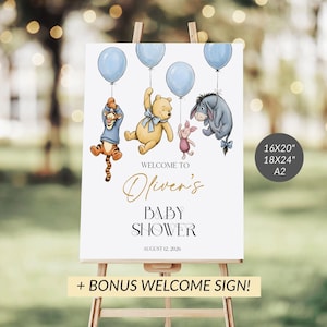 May include: A white baby shower sign on an easel features Winnie the Pooh characters holding blue balloons. The sign reads "Welcome to Oliver's Baby Shower" with the date August 12, 2026. Includes a bonus welcome sign.