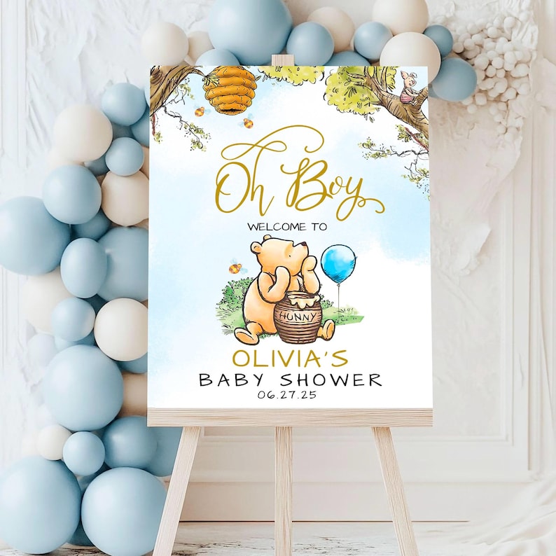May include: Winnie the Pooh themed baby shower welcome sign with a blue and white watercolor background. The sign says "Oh Boy" in gold script, "Welcome to Olivia's Baby Shower" and the date "06.27.25".