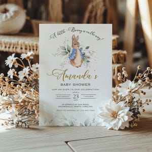Peut inclure: Une invitation &agrave; une f&ecirc;te pr&eacute;natale avec une illustration aquarelle d'un lapin portant une veste bleue. L'invitation est pour la f&ecirc;te pr&eacute;natale d'Amanda le 23 avril 2025 &agrave; 19h00. L'adresse est 18 Upper Flat Oak Road, Weaverville, Caroline du Nord. RSVP &agrave; Amanda au 123-456-7890.