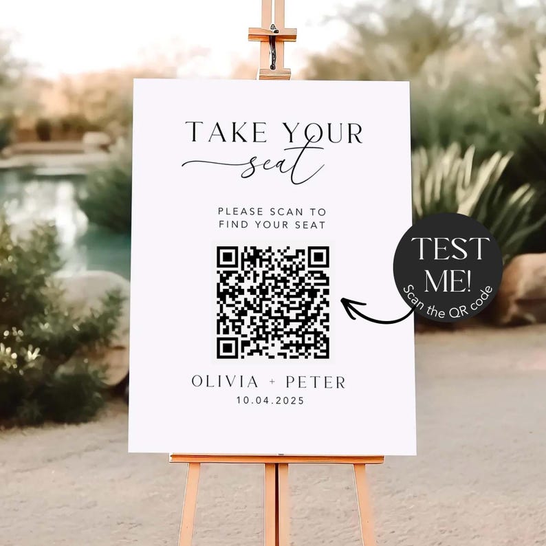 May include: A white sign on a wooden easel with the text "TAKE YOUR seat" in elegant script. Below, it reads "PLEASE SCAN TO FIND YOUR SEAT" with a QR code. A black circle with "TEST ME! Scan the QR code" is on the right. The names Olivia + Peter and the date 10.04.2025 are at the bottom.