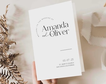 May include: A white wedding program card featuring black text that reads Welcome to the wedding of Amanda and Oliver, the date 05.07.25, and the location St. Mary's Church, San Diego, California, with a simple horizontal line design.
