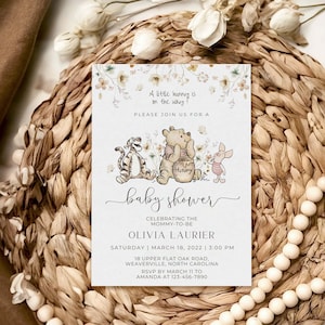 May include: A Winnie the Pooh themed baby shower invitation with a watercolor floral background. The invitation features Winnie the Pooh, Tigger, and Piglet. The text reads "A little hunny is on the way! Please join us for a baby shower celebrating the mommy-to-be Olivia Laurier. Saturday | March 18, 2022 | 3:00 PM. 18 Upper Flat Oak Road, Weaverville, North Carolina. RSVP by March 11 to Amanda at 123-456-7890."