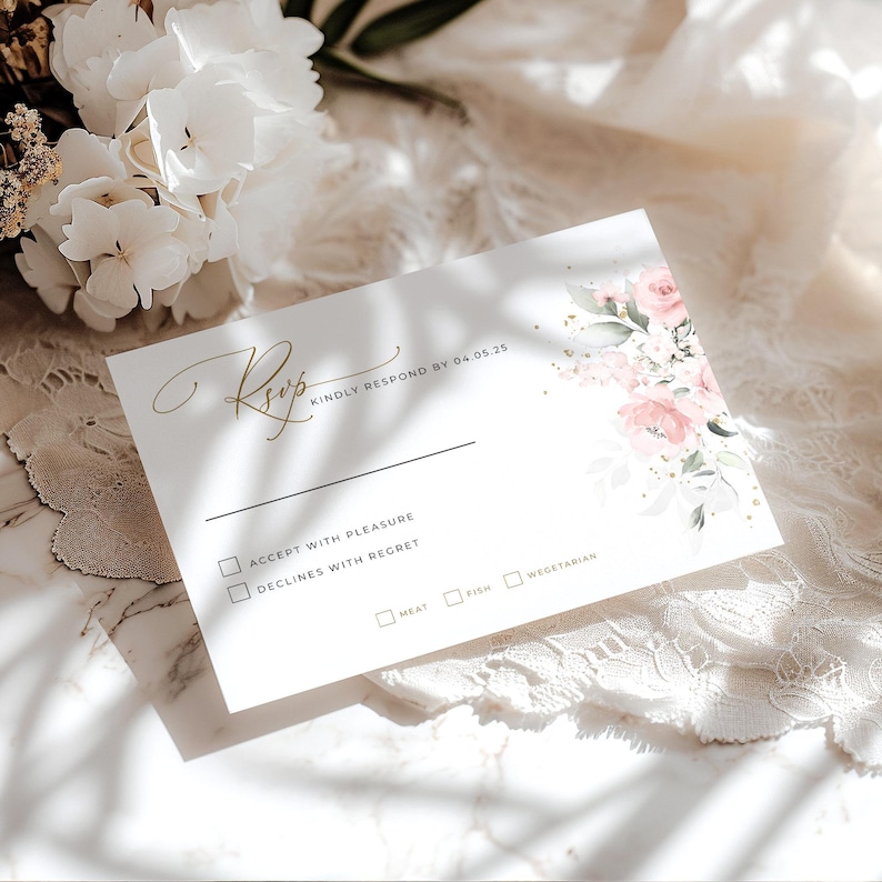 May include: A white RSVP card with gold lettering and a floral design. The text reads "RSVP KINDLY RESPOND BY 04.05.25". The card has checkboxes for accepting or declining the invitation, and for meal choices.