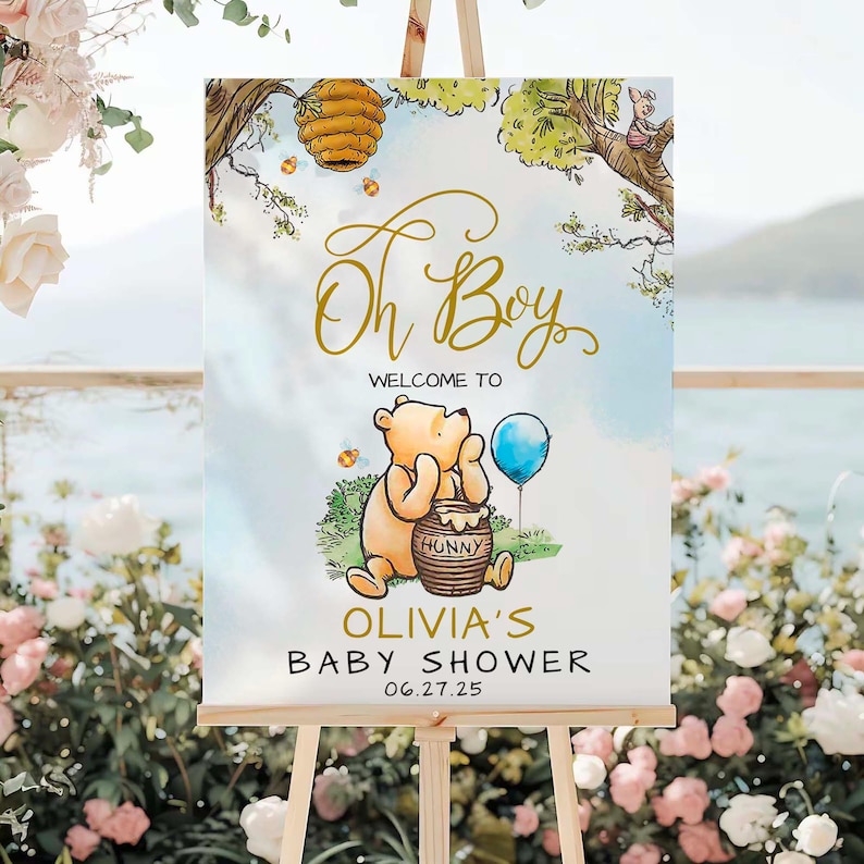 May include: A Winnie the Pooh themed baby shower sign with a blue and white watercolor background. The sign features Winnie the Pooh holding a pot of honey and a blue balloon. The text on the sign reads "Oh Boy" in gold script, "Welcome to Olivia's Baby Shower" and "06.27.25".