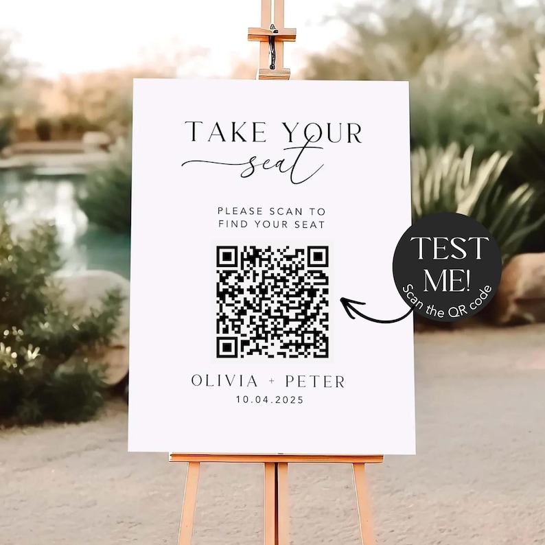 May include: A white sign on a wooden easel with the text "TAKE YOUR seat" in elegant script. Below, it reads "PLEASE SCAN TO FIND YOUR SEAT" with a QR code. The sign also includes the names "OLIVIA + PETER" and the date "10.04.2025". A black circle with the text "TEST ME! Scan the QR code" is on the right.