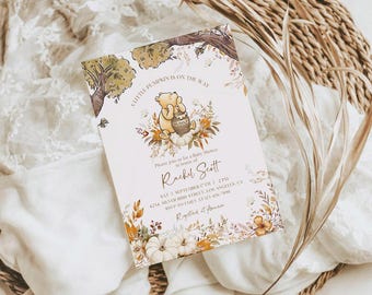 May include: A rectangular baby shower invitation card featuring a watercolour illustration of Winnie the Pooh with a honey pot, surrounded by autumn leaves, pumpkins, and trees. The text reads A LITTLE PUMPKIN IS ON THE WAY, Rachel Scott, and event details.