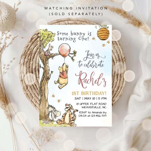 以下が含まれることがあります： くまのプーさんテーマの1歳の誕生日パーティー招待状。水彩画で描かれたプーさん、ピグレット、イーヨー、ティガーのイラストが描かれています。招待状には「Some hunny is turning One!」「Join us to celebrate Rachel's 1st Birthday!」のテキストと、パーティーの日時、住所、RSVP情報が記載されています。