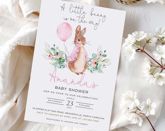 May include: A baby shower invitation card featuring a watercolor illustration of a brown bunny holding a pink balloon, surrounded by greenery. The text reads: A little bunny is on the way! Amanda's BABY SHOWER, Saturday April 23 2025, 7 o'clock.