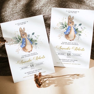 Peut inclure: Une invitation &agrave; une f&ecirc;te pr&eacute;natale avec une illustration aquarelle d'un lapin portant une veste bleue et entour&eacute; de verdure. L'invitation est pour Amanda Roberts et comprend la date, l'heure et le lieu de la f&ecirc;te.