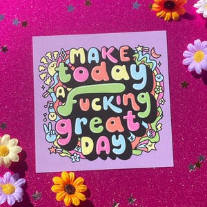 Könnte beinhalten: Ein quadratischer lila Druck mit dem Text "MAKE today A fucking great DAY" in bunten Buchstaben. Der Druck ist von bunten Blumen und sternförmigem Konfetti auf einem rosa Glitzerhintergrund umgeben.