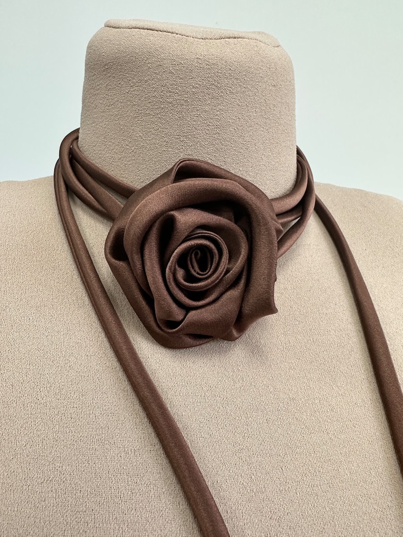May include: A brown satin choker necklace with a large brown satin rose accent.