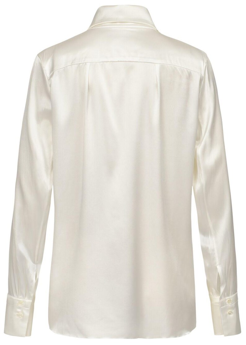 Puede incluir: Una camisa de manga larga con botones en un color blanco roto s&oacute;lido con un acabado suave y brillante. La camisa presenta un cuello cl&aacute;sico, un canes&uacute; en la espalda y pu&ntilde;os con dos botones en cada manga, vista desde la parte posterior.