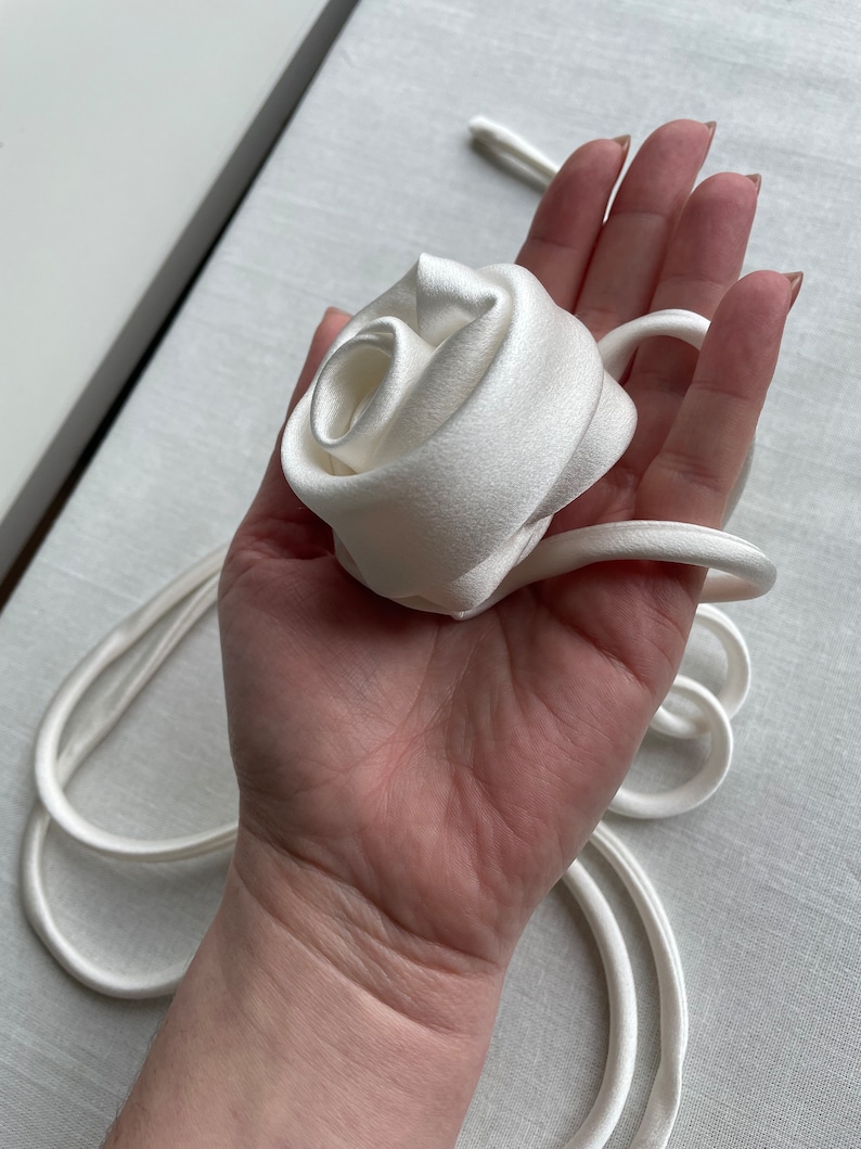 May include: A white satin ribbon tied into a rose shape.