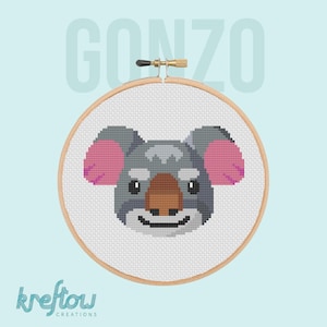 May include: A cross-stitch embroidery of a koala bear's face, featuring gray fur, pink ears, and a brown nose, set within a wooden embroidery hoop. The word "GONZO" is above the hoop, and "kreftow creations" is below.