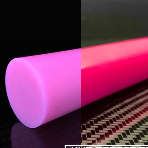 Puede incluir: Una varilla redonda y sólida de resina de color rosa brillante. La varilla es lisa y brillante. La varilla se muestra sobre un fondo negro y un fondo de fibra de carbono.