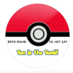 Może przedstawiać: Czerwona, biała i czarna bomba do kąpieli w kształcie Pok&eacute; Balla z napisem "Bath Bomb" i "Do Not Eat" na g&oacute;rze oraz napisem "Ben is the Bomb!" na dole.