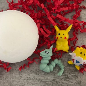 Może przedstawiać: Biała piłka z pianki, ż&oacute;łta figurka Pikachu z mrugającym okiem, zielona figurka gąsienicy i biała i ż&oacute;łta figurka w kształcie jajka z niebieskim wzorem tr&oacute;jkąta.