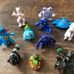 Może przedstawiać: Kolekcja dziesięciu małych plastikowych figurek Pokemon&oacute;w. Figurki są w r&oacute;żnych kolorach, w tym niebieskim, r&oacute;żowym, zielonym i czarnym. Figurki są w r&oacute;żnych pozach, a niekt&oacute;re mają detale, takie jak oczy, usta i pazury.