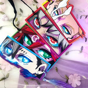 May include: A set of anime-style bookmarks, each depicting a close-up of eyes in vivid colours. The rectangular bookmarks have coloured borders and black strings. Each bookmark is finished with a decorative tassel, adding a touch of flair to the design.