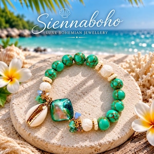 May include: A beaded bracelet featuring round turquoise-coloured beads with brown veining, white carved floral beads, and small gold-toned spacers. A large square iridescent green shell charm and a white cowrie shell charm hang from the bracelet.