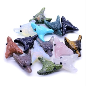 May include: A collection of 14 carved crystal wolf head pendants in various colors, including brown, green, blue, pink, and black. The pendants are made of natural stones and have black eyes.