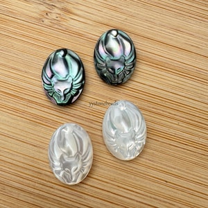 Puede incluir: Cuatro cabujones ovalados de madreperla con un diseño de zorro tallado. Dos cabujones son de color negro y verde iridiscente, y dos son blancos.