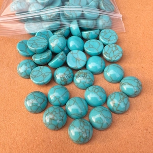 May include: A selection of turquoise-coloured, round beads with a mottled, brown-veined pattern. The beads are scattered on a surface, with some spilling from a clear plastic bag. These beads are likely for jewellery making or crafts.