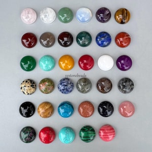 May include: A collection of thirty-five circular, polished gemstone cabochons arranged in six rows. The beads display a variety of colours and patterns, including solid, speckled, and striped textures in shades of red, blue, green, black, white, and brown.