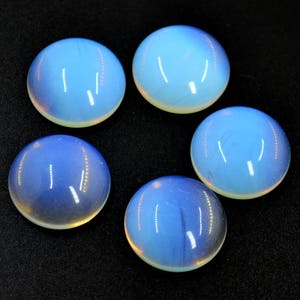 May include: Five round, iridescent opal cabochons in various shades of blue and white. The cabochons are smooth and polished, with a slightly domed shape.