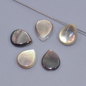 May include: Five iridescent pearlescent teardrop shaped shell beads. The beads are a mix of light and dark colours with a pearlescent sheen.