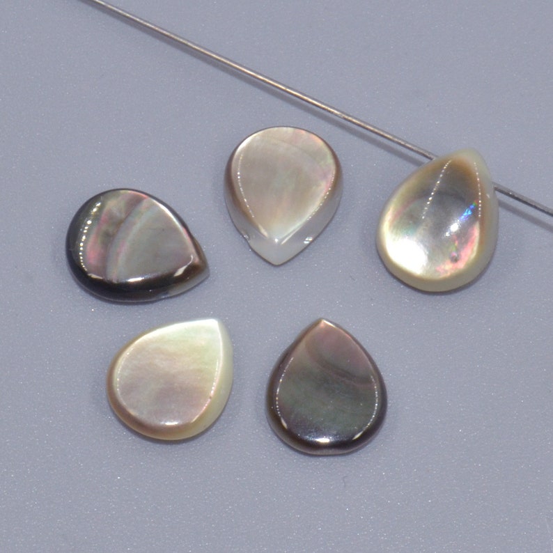 May include: Five iridescent pearlescent teardrop shaped shell beads. The beads are a mix of light and dark colours with a pearlescent sheen.