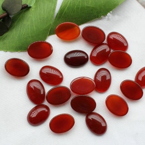 Puede incluir: Una colección de 18 cabujones de cornalina roja de forma ovalada, perfectos para la elaboración de joyas o manualidades.