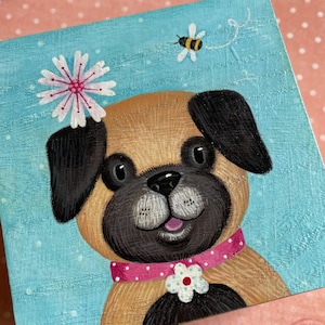 May include: A square painting of a pug dog with a pink collar and a flower on its head. The dog has a light brown coat, black ears, and a black snout. A bee flies near the dog's head against a light blue background.