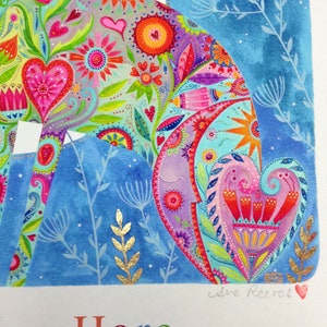 Op de afbeelding: Een kleurrijk aquarel schilderij van een blauwe haas met een bloemenpatroon. De haas is omringd door een blauwe achtergrond met gouden accenten. Het schilderij is onderaan rechts gesigneerd met "Jane Reeves" en onderaan links met "Blue Hare" betiteld.