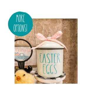 May include: White ceramic canister with a teal blue "Easter Eggs" inscription and a pink gingham ribbon tied around the lid.