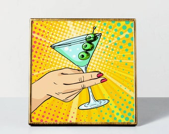 May include: A yellow, red, and blue pop art style illustration of a hand holding a martini glass with green olives. The background is a yellow and blue radial pattern.