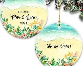 May include: Two round ceramic ornaments with a beach scene. The first ornament says "ENGAGED Mike & Lauren 10.12.18". The second ornament says "She Said Yes!"