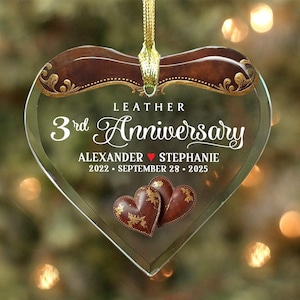 May include: A heart-shaped ornament with a leather design. The ornament features the text "3rd Anniversary" and the names "Alexander" and "Stephanie" with a heart symbol. Two brown hearts with gold accents are at the bottom.