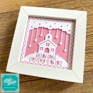 May include: White paper cut-out art in a white frame. The design features a church, stars, hearts, and clouds. The text reads "Willow Grace Christened 12.06.2022".