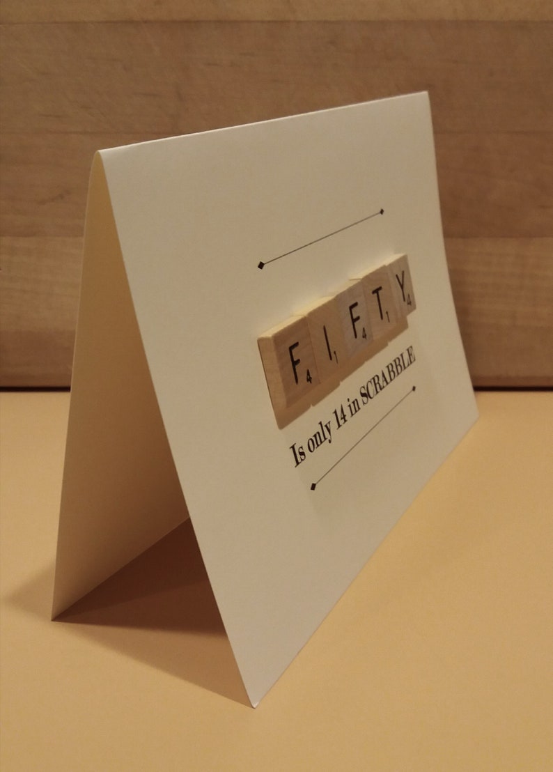 May include: A white card with the word "FIFTY" spelled out in Scrabble tiles. The text below reads "Is only 14 in SCRABBLE".