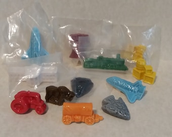 May include: A collection of ten miniature ceramic figurines, each depicting a different mode of transport. The figurines are in various colours, including red, blue, green, yellow, orange, and brown. The figurines are packaged in individual plastic bags.