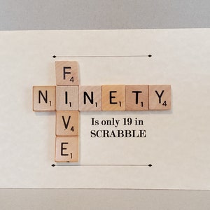 May include: A white card with the word "NINETY" spelled out using Scrabble tiles. The tiles are arranged in a cross shape. The text "Is only 19 in SCRABBLE" is printed below the tiles.