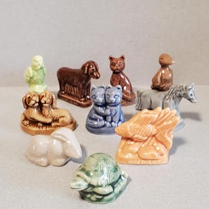 May include: A collection of ten small ceramic figurines of various animals, including a turtle, a rabbit, a fish, a cat, a dog, a bird, and a horse. The figurines are all in different colors and have a vintage look.