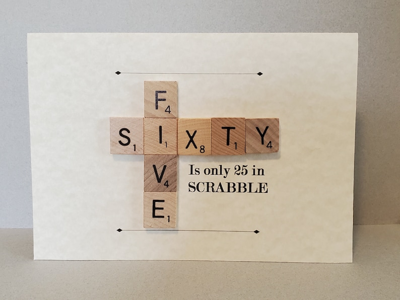 May include: A card with the word "SIXTY" spelled out using Scrabble tiles. The text "Is only 25 in SCRABBLE" is written below the tiles.