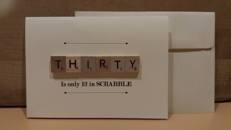 Puede incluir: Una tarjeta blanca con un sobre marr&oacute;n. La tarjeta tiene un fondo blanco con texto negro y una fila de fichas de letras de madera que deletrean "THIRTY". El texto debajo de las fichas dice "Is only 12 in SCRABBLE".