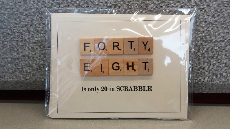 May include: A white card with the word "FORTY-EIGHT" spelled out using Scrabble tiles. The text below the tiles reads "Is only 20 in SCRABBLE".